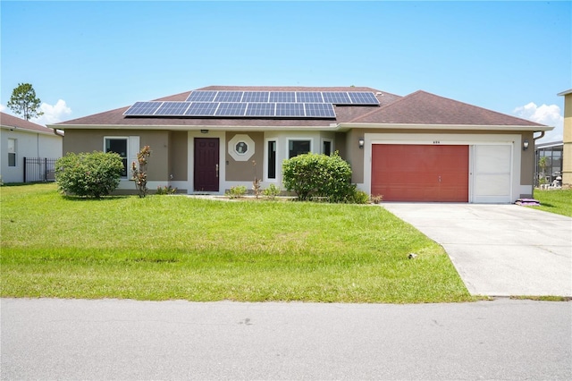 ranch-style home featuring solar panels, a garage, and a front lawn