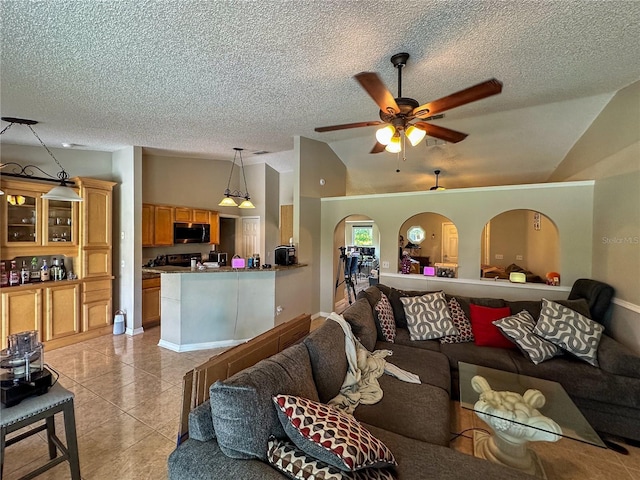 living room with arched walkways, lofted ceiling, light tile patterned flooring, ceiling fan, and a textured ceiling