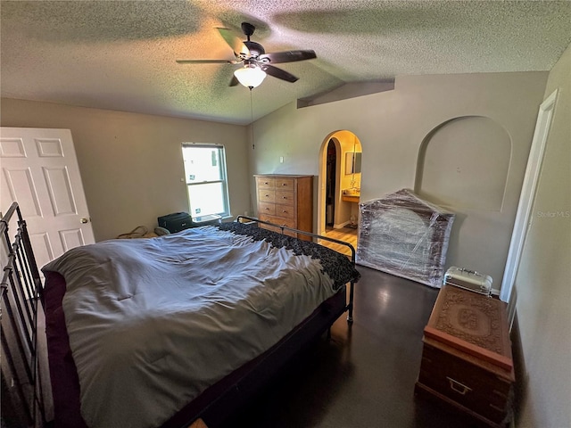 bedroom featuring wood-type flooring, a textured ceiling, ensuite bathroom, ceiling fan, and lofted ceiling