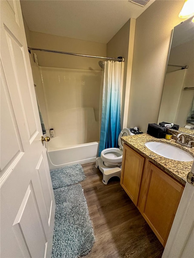 full bathroom with hardwood / wood-style floors, toilet, shower / bathtub combination with curtain, and vanity