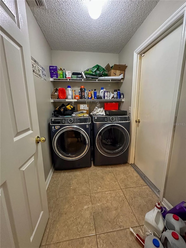 laundry area featuring a textured ceiling, light tile patterned flooring, and separate washer and dryer