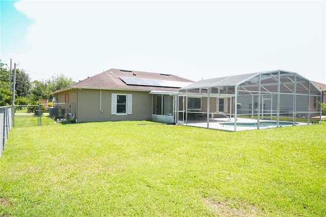 rear view of house featuring a lawn, solar panels, a fenced in pool, and a lanai