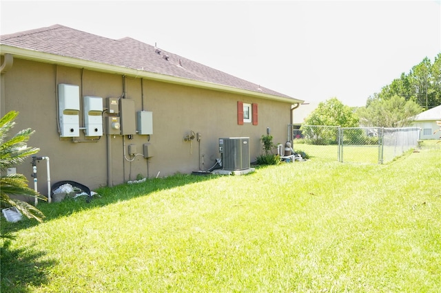 rear view of property with a yard and central AC