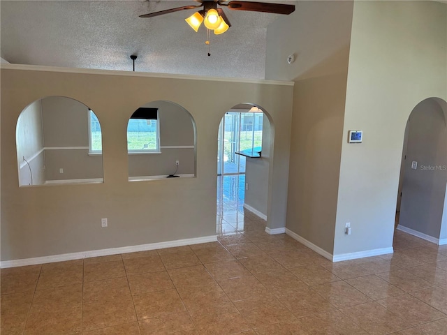 tiled spare room with arched walkways, baseboards, a textured ceiling, and a ceiling fan