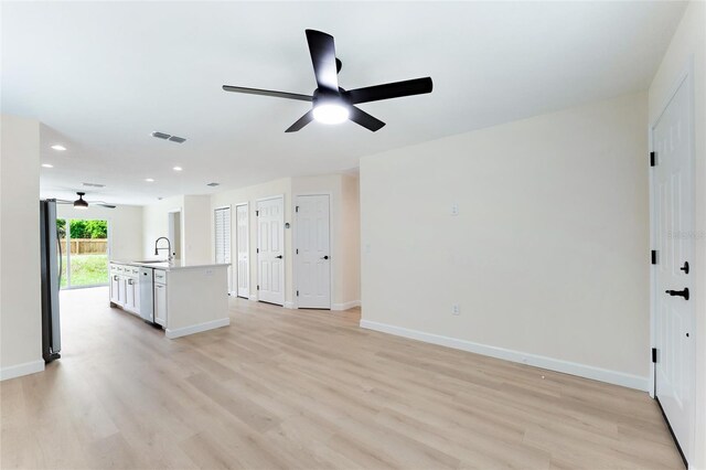 unfurnished living room featuring ceiling fan, light wood-type flooring, and sink