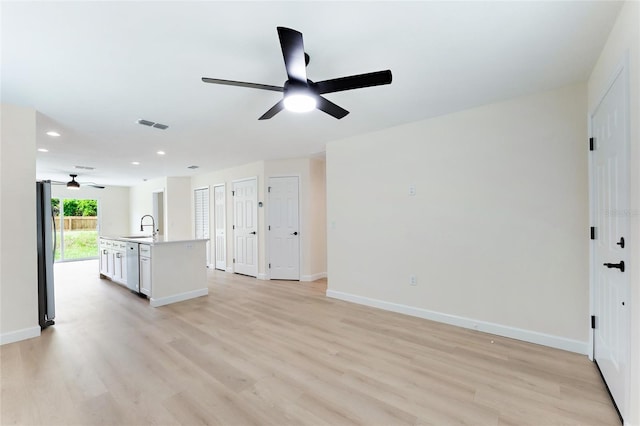 unfurnished living room featuring sink, light wood-type flooring, and ceiling fan