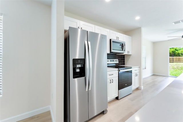 kitchen featuring appliances with stainless steel finishes, light hardwood / wood-style flooring, decorative backsplash, ceiling fan, and white cabinetry