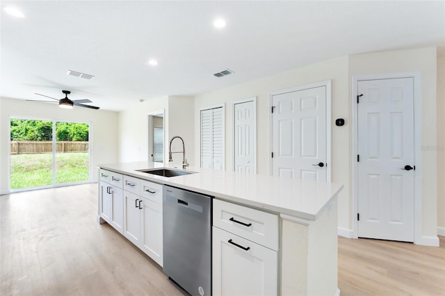 kitchen featuring white cabinets, light wood-type flooring, an island with sink, ceiling fan, and stainless steel dishwasher