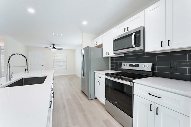 kitchen featuring light hardwood / wood-style flooring, appliances with stainless steel finishes, backsplash, ceiling fan, and sink