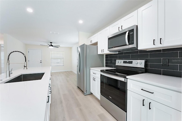 kitchen featuring light hardwood / wood-style flooring, sink, stainless steel appliances, white cabinets, and tasteful backsplash