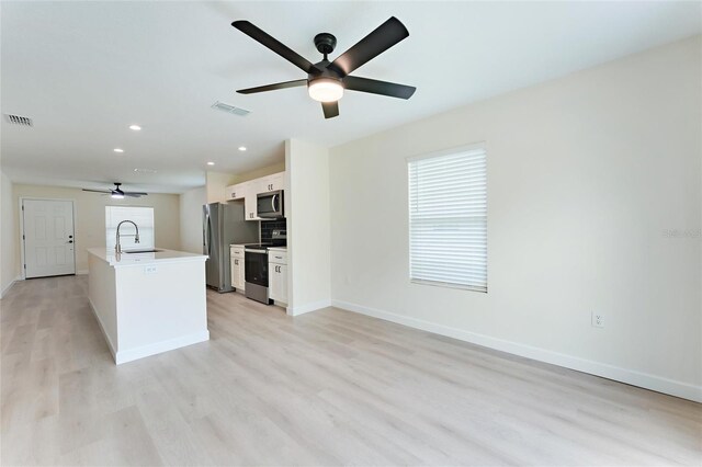 kitchen featuring stainless steel appliances, ceiling fan, sink, white cabinetry, and light hardwood / wood-style flooring