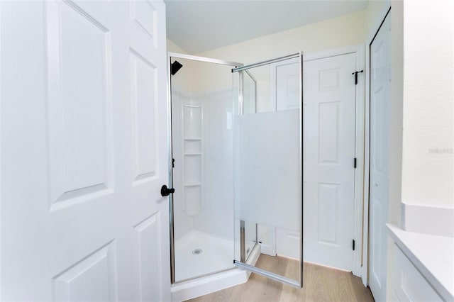 bathroom with hardwood / wood-style flooring and an enclosed shower