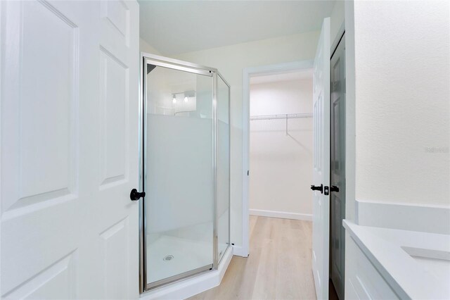 bathroom with vanity, a shower with door, and wood-type flooring