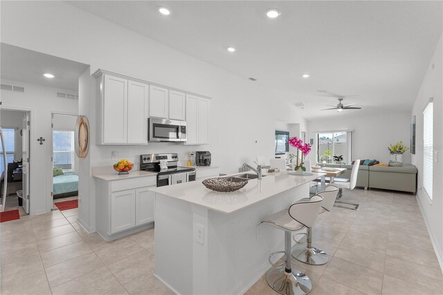 kitchen featuring stainless steel appliances, plenty of natural light, and a center island with sink