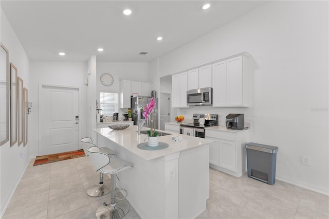 kitchen with a center island with sink, vaulted ceiling, appliances with stainless steel finishes, and white cabinetry