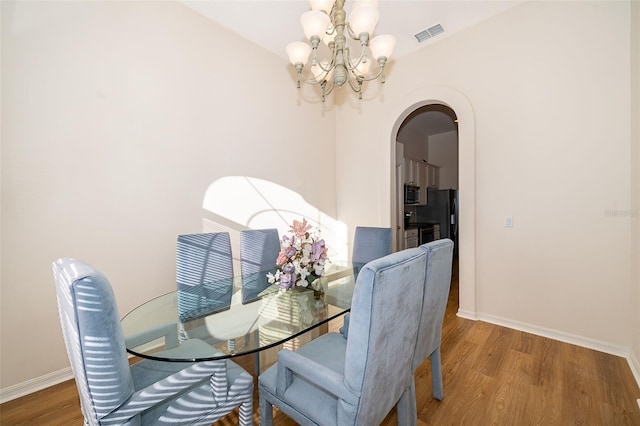 dining room with wood-type flooring and a notable chandelier