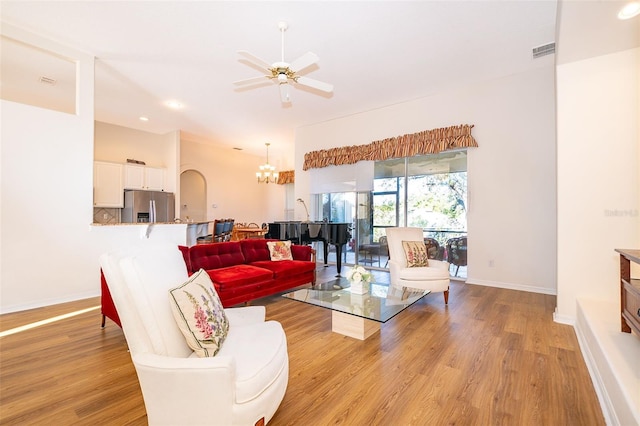 living room with ceiling fan with notable chandelier and light wood-type flooring