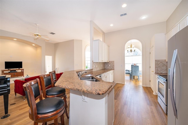 kitchen with appliances with stainless steel finishes, tasteful backsplash, white cabinetry, sink, and kitchen peninsula