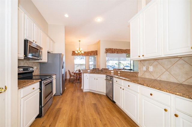 kitchen with hanging light fixtures, decorative backsplash, stainless steel appliances, and white cabinets