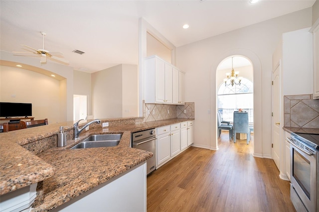 kitchen featuring ceiling fan with notable chandelier, sink, white cabinets, backsplash, and light stone counters