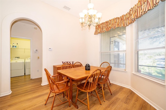 dining space with washing machine and dryer, a notable chandelier, and light wood-type flooring