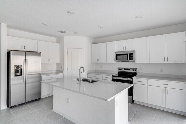 349 River Front Way, Edgewater, FL 32141 - kitchen with sink, white cabinetry, light tile patterned floors, appliances with stainless steel finishes, and an island with sink
