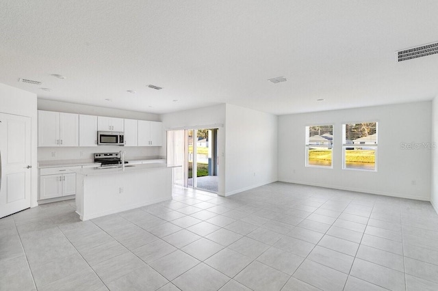 349 River Front Way, Edgewater, FL 32141 - kitchen featuring stainless steel appliances, light tile patterned flooring, a center island with sink, and white cabinets