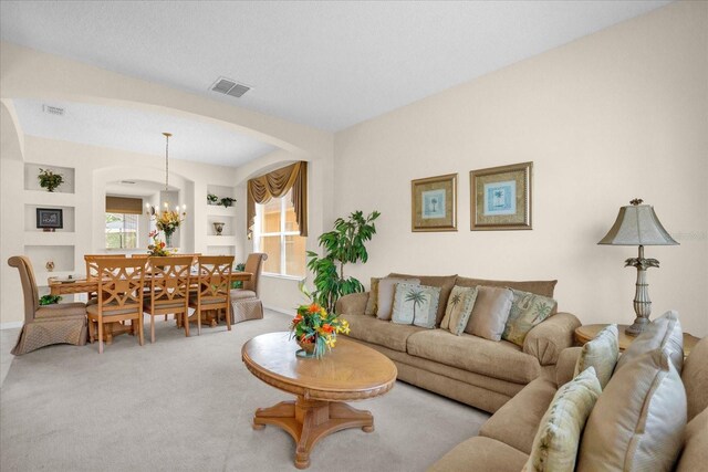 living room featuring light carpet, a notable chandelier, and a wealth of natural light