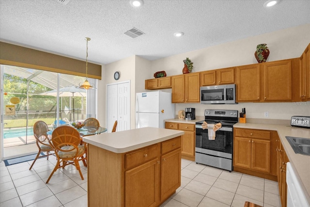 kitchen featuring a center island, decorative light fixtures, a textured ceiling, light tile patterned floors, and stainless steel appliances