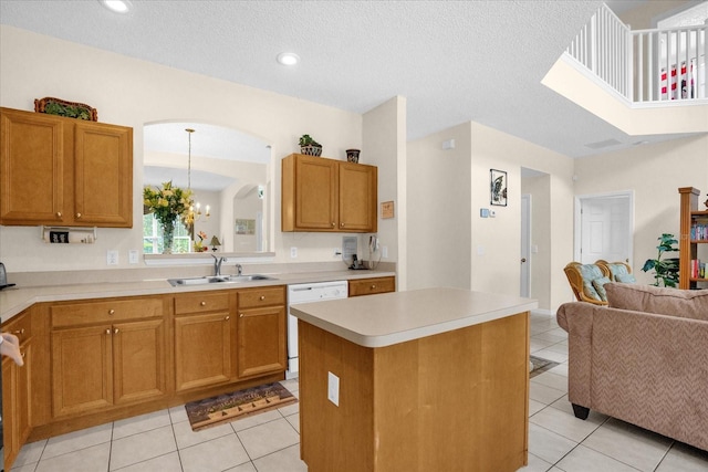 kitchen featuring a kitchen island, dishwasher, light tile patterned floors, sink, and a textured ceiling