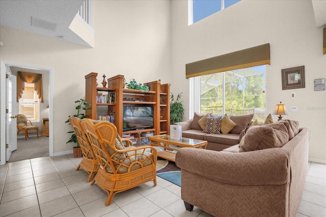 living room featuring light tile patterned flooring, a high ceiling, and a textured ceiling