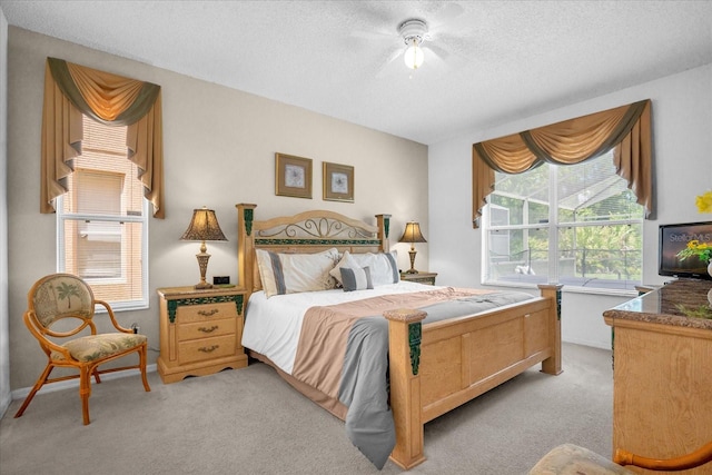 bedroom with ceiling fan, light carpet, and a textured ceiling