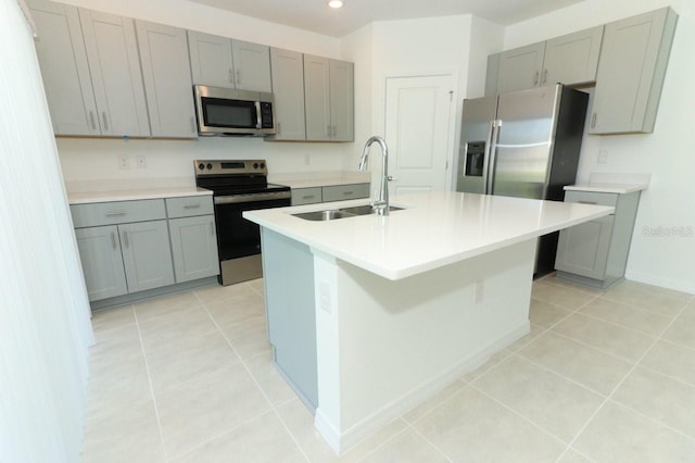 kitchen featuring a kitchen island with sink, sink, light tile patterned floors, and appliances with stainless steel finishes