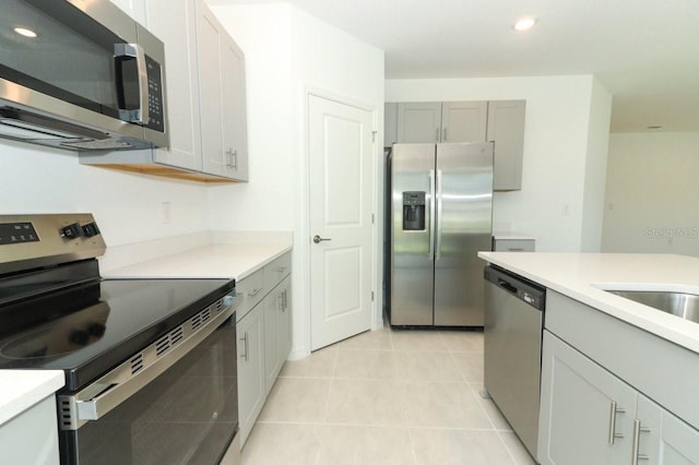 kitchen featuring light tile patterned flooring, stainless steel appliances, and gray cabinets