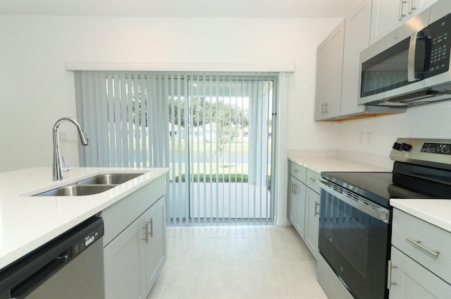 kitchen with stainless steel appliances, light tile patterned flooring, sink, and white cabinets