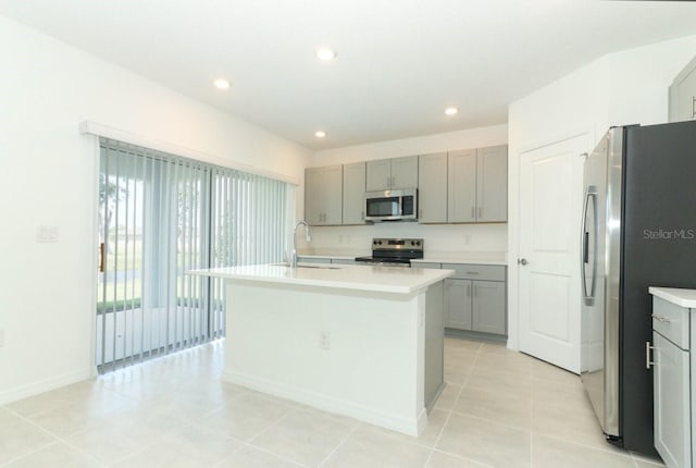 kitchen featuring gray cabinetry, sink, stainless steel appliances, and an island with sink