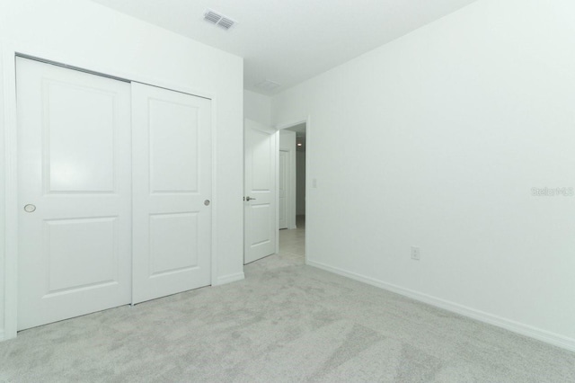 unfurnished bedroom featuring light carpet and a closet