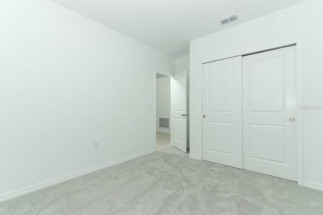 unfurnished bedroom with light carpet and a closet