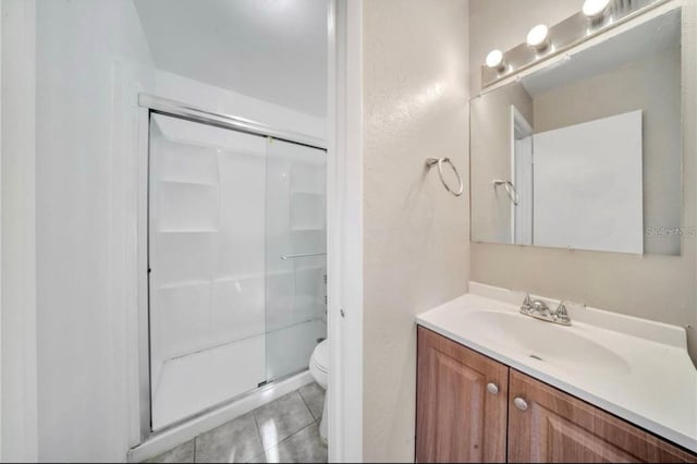 bathroom with an enclosed shower, vanity, tile patterned flooring, and toilet