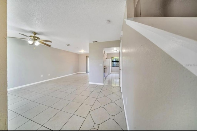 unfurnished room with ceiling fan, light tile patterned flooring, and a textured ceiling