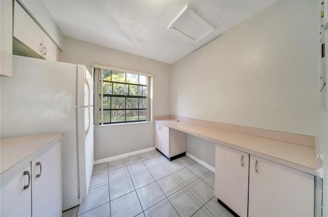 kitchen with light tile patterned flooring, white fridge, and white cabinetry