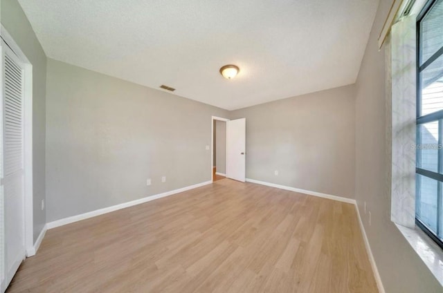 interior space featuring a textured ceiling, light hardwood / wood-style floors, and a closet