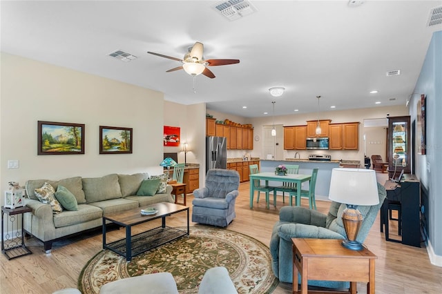 living room with ceiling fan, sink, and light hardwood / wood-style floors