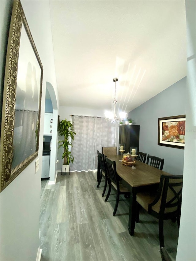 dining area featuring vaulted ceiling, a chandelier, and hardwood / wood-style floors