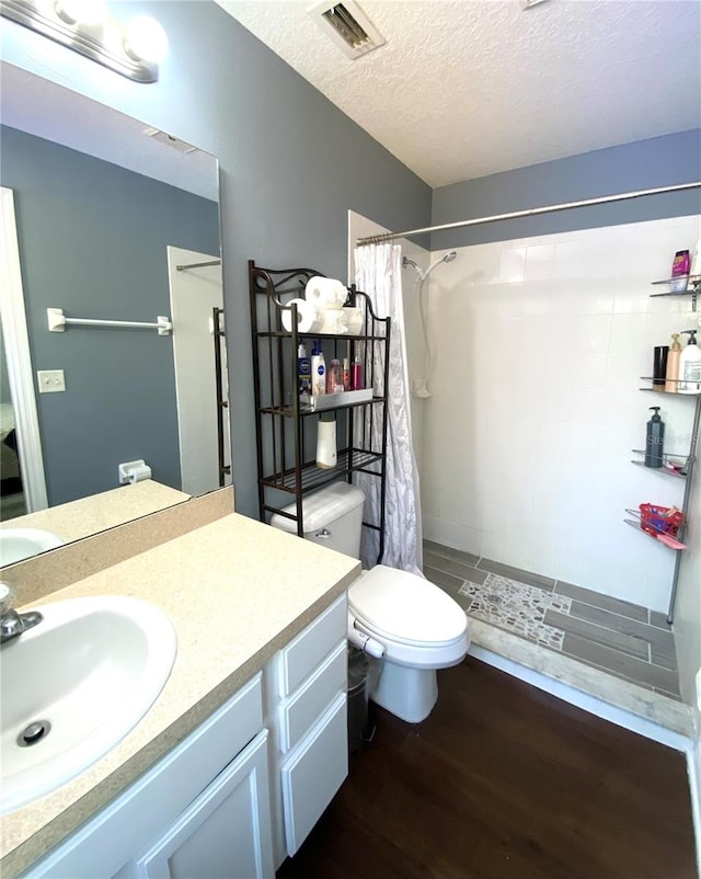 bathroom with a textured ceiling, toilet, vanity, hardwood / wood-style flooring, and a shower with shower curtain