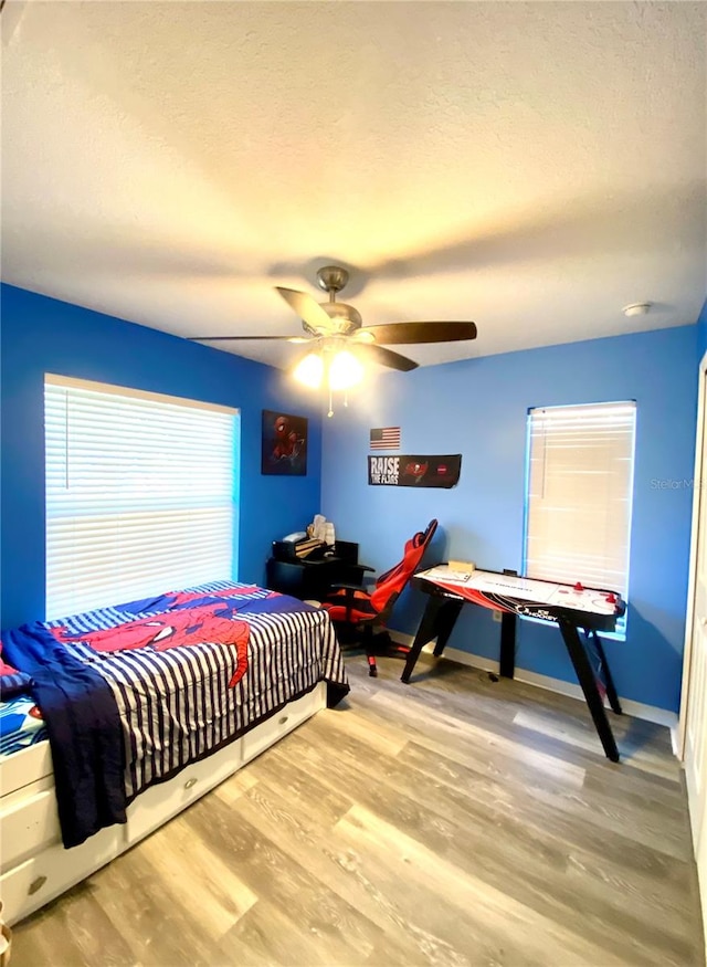 bedroom featuring a textured ceiling, light wood-type flooring, and ceiling fan