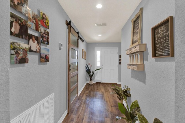 doorway to outside featuring a barn door and dark wood-type flooring