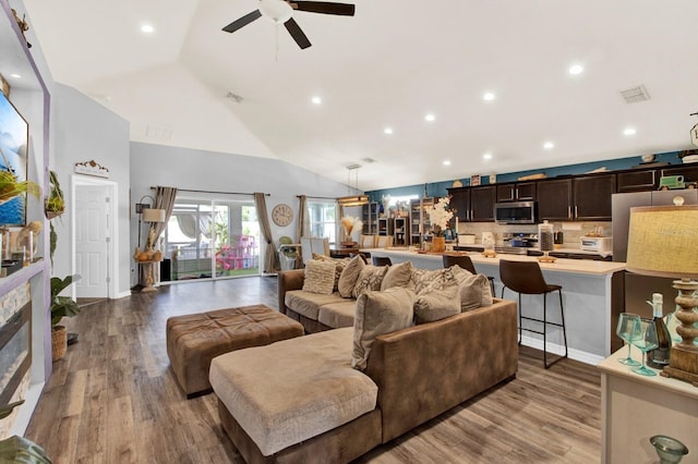 living room featuring high vaulted ceiling, light hardwood / wood-style flooring, ceiling fan, and a fireplace