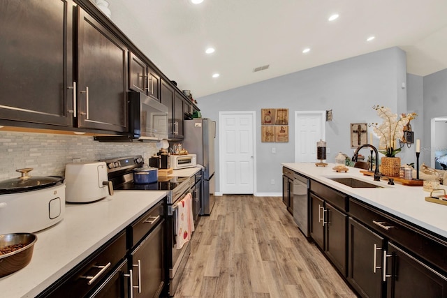 kitchen with lofted ceiling, stainless steel appliances, sink, tasteful backsplash, and light hardwood / wood-style floors