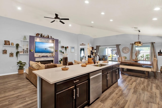 kitchen featuring dishwasher, an island with sink, decorative light fixtures, vaulted ceiling, and sink